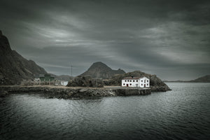 Antiguo edificio noruego blanco en una costa rocosa del puerto