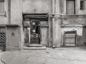Facciata di un vecchio edificio rumeno con una porta danneggiata e tubazioni a vista